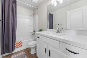 Full bathroom with hardwood / wood-style flooring, toilet, vanity, and shower / bath combo