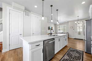 Kitchen featuring white cabinets, appliances with stainless steel finishes, sink, pendant light fixtures, and large kitchen island with sink