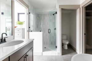 Bathroom with a shower with shower door, vanity, tile patterned flooring, and toilet