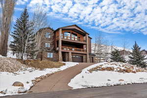 View of front of home with a garage and a balcony