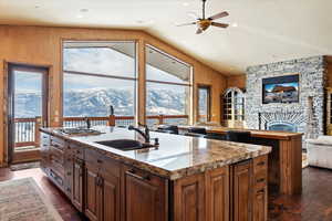 Kitchen featuring sink, a healthy amount of sunlight, a kitchen island with sink, and a fireplace