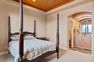 Bedroom with sink, a tray ceiling, and ensuite bath