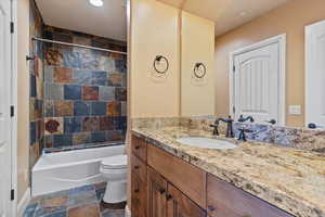 Full bathroom featuring toilet, tiled shower / bath combo, and vanity