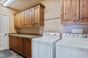 Clothes washing area featuring washing machine and dryer and cabinets