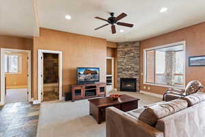 Carpeted living room with ceiling fan, plenty of natural light, and a fireplace