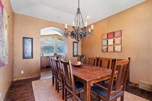 Dining room featuring dark wood-type flooring, lofted ceiling, and an inviting chandelier