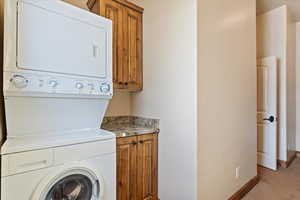 Clothes washing area with stacked washer / drying machine and cabinets