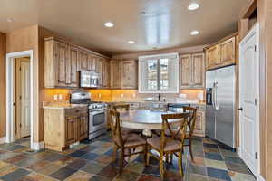 Kitchen featuring appliances with stainless steel finishes, light stone counters, and sink