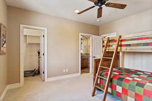 Bedroom with ceiling fan, light colored carpet, ensuite bathroom, a spacious closet, and a closet