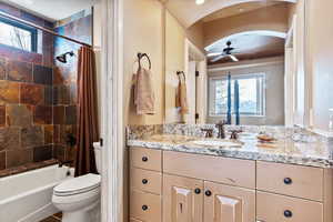 Full bathroom featuring ceiling fan, toilet, vanity, and shower / bathtub combination with curtain