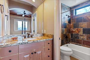 Full bathroom with toilet, ceiling fan, tiled shower / bath, and vanity