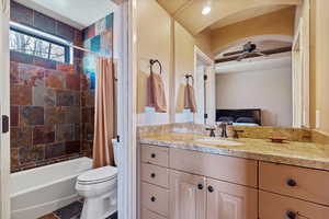 Full bathroom featuring toilet, ceiling fan, shower / bathtub combination with curtain, and vanity