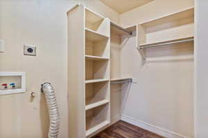 Walk in closet with dark hardwood / wood-style flooring