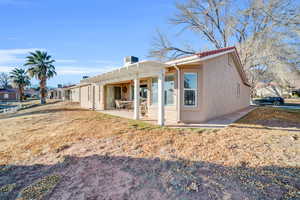 Rear view of property featuring a lawn, a pergola, and a patio