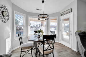 Dining area with light wood-type flooring and a notable chandelier