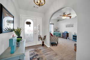 Entryway featuring ceiling fan with notable chandelier and light hardwood / wood-style floors