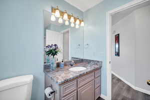 Bathroom with hardwood / wood-style flooring, toilet, and vanity