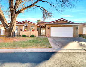 Ranch-style house with a tile roof, stucco siding, an attached garage, a front yard, and driveway