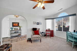 Living area with ceiling fan with notable chandelier and carpet