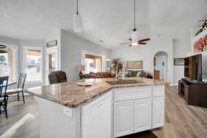 Kitchen featuring white dishwasher, an island with sink, hanging light fixtures, and sink