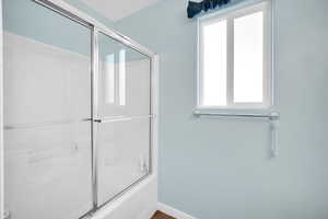 Bathroom with bath / shower combo with glass door and a wealth of natural light