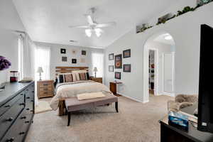 Carpeted bedroom featuring ceiling fan, multiple windows, and a spacious closet