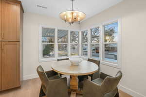 Dining room with a wealth of natural light, a chandelier, and light hardwood / wood-style flooring