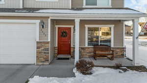 Snow covered property entrance with a porch