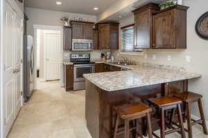 Kitchen featuring sink, kitchen peninsula, stainless steel appliances, and a breakfast bar