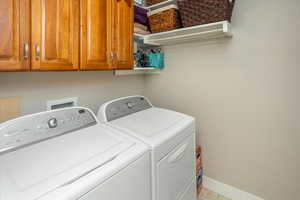 Washroom featuring cabinets, independent washer and dryer, and light tile patterned flooring