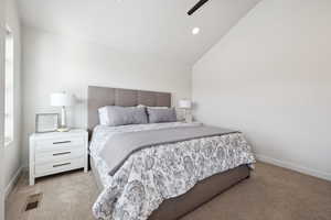 Carpeted bedroom with lofted ceiling, baseboards, and visible vents