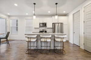 Kitchen featuring a center island with sink, stainless steel appliances, backsplash, a sink, and a kitchen bar