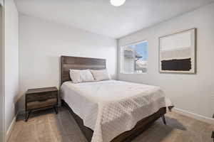 Bedroom with light colored carpet, a textured ceiling, and baseboards