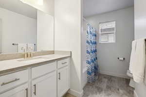 Full bathroom featuring marble finish floor, curtained shower, toilet, vanity, and baseboards