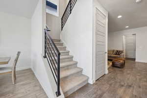 Staircase featuring recessed lighting, baseboards, and wood finished floors