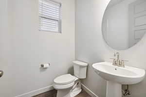 Bathroom with toilet, baseboards, and wood finished floors