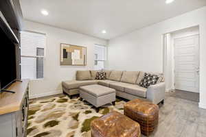 Living area with baseboards, recessed lighting, and light wood-style floors