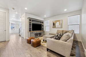 Living room featuring light wood finished floors, stairway, recessed lighting, and baseboards