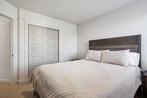 Carpeted bedroom with a textured ceiling, baseboards, and a closet