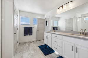 Bathroom featuring baseboards, double vanity, a sink, and a shower stall