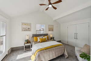 Carpeted bedroom with ceiling fan, a closet, and vaulted ceiling with beams