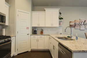 Kitchen featuring light stone counters, sink, white cabinets, and appliances with stainless steel finishes