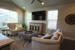 Living room featuring vaulted ceiling, ceiling fan, a wealth of natural light, and dark hardwood / wood-style flooring