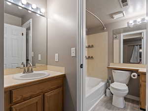 Full bathroom featuring toilet, hardwood / wood-style floors, bathtub / shower combination, a textured ceiling, and vanity