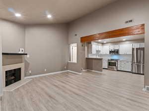 Unfurnished living room featuring a towering ceiling and light hardwood / wood-style floors