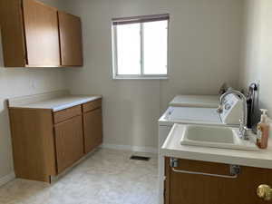 Laundry room featuring washing machine and dryer, cabinets, and sink