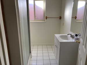 Bathroom featuring tile patterned flooring, an enclosed shower, and vanity