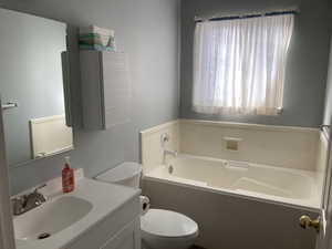 Bathroom featuring a tub to relax in, vanity, and toilet