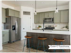 Kitchen featuring light hardwood / wood-style floors, appliances with stainless steel finishes, decorative light fixtures, backsplash, and a breakfast bar area