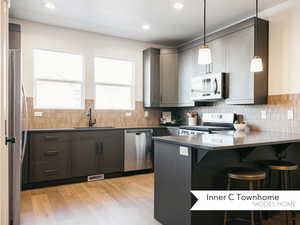 Kitchen featuring a kitchen bar, hanging light fixtures, sink, kitchen peninsula, and stainless steel appliances